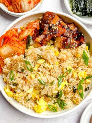 Gyeran Bokkeumbapin a white bowl with kimchi and fried pork belly.
