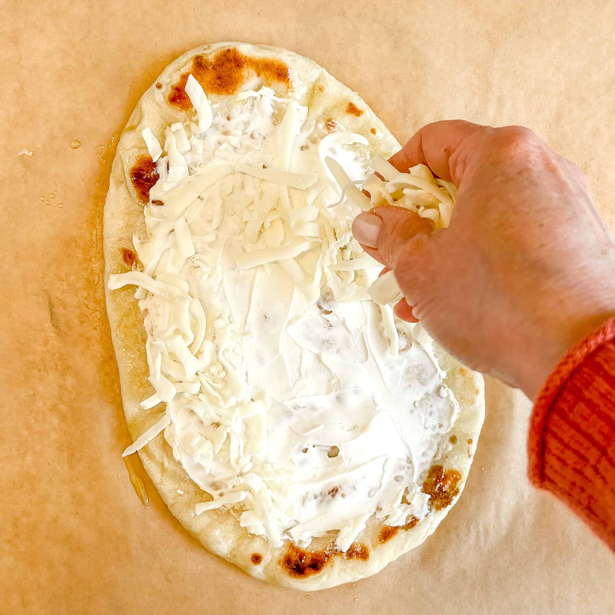 Placing cheese on a Naan Breakfast Pizza.