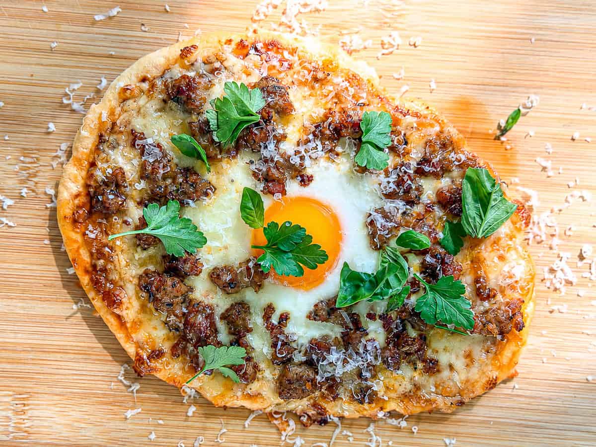 Flatbread pizza on a wooden cutting board.