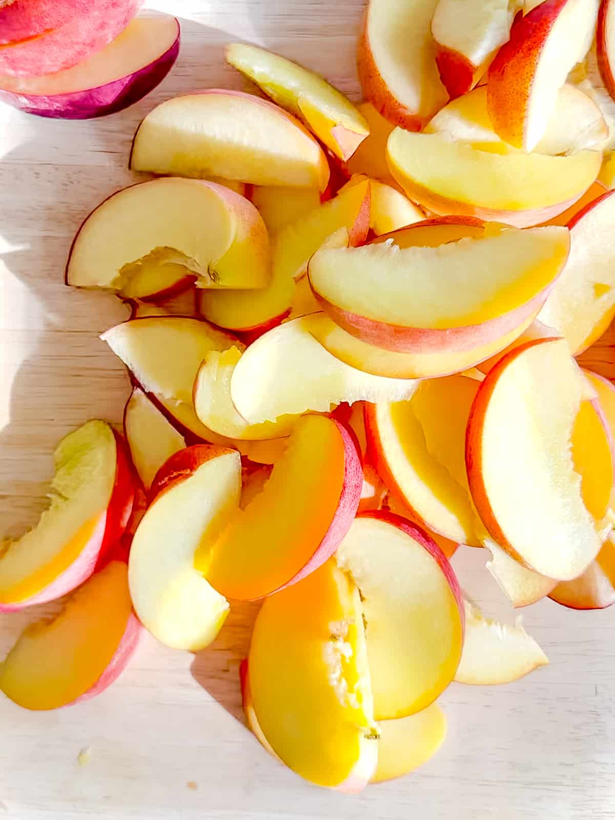 Sliced peaches on wooden cutting board.