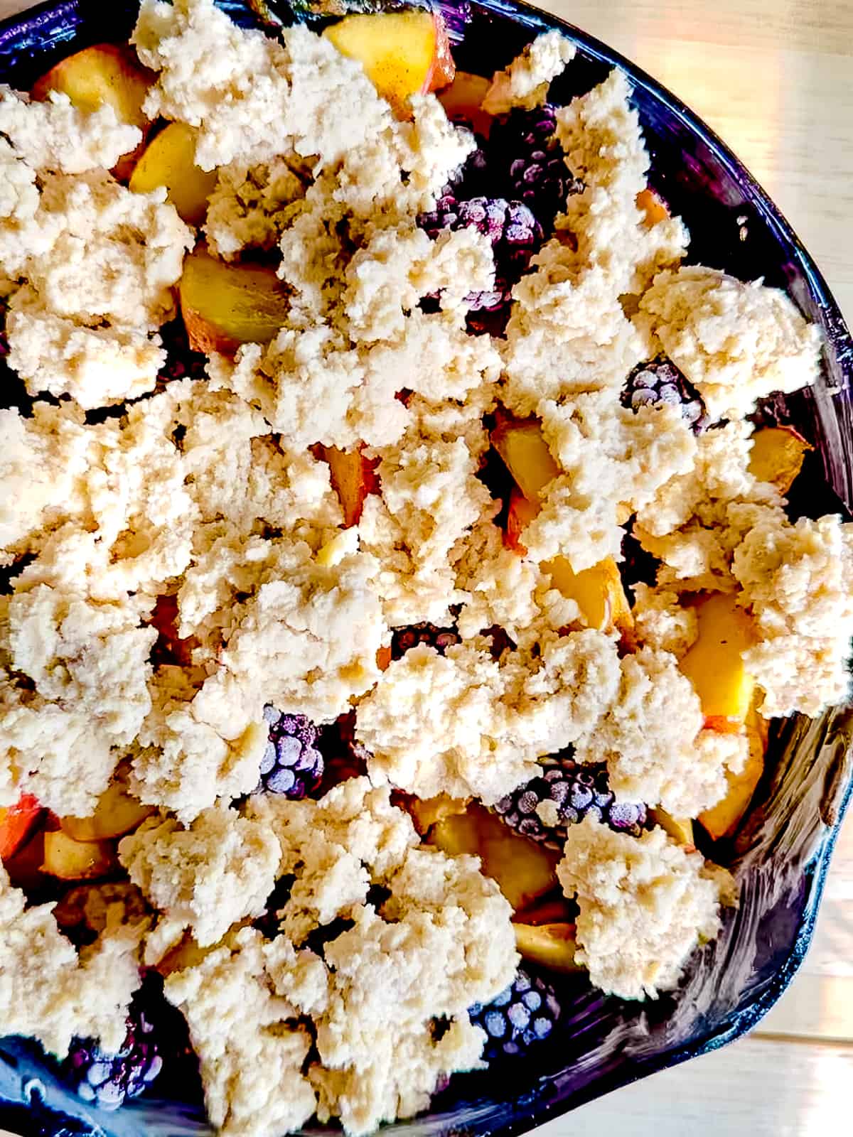 Biscuit topping completely covering blackberry peach cobbler filling.