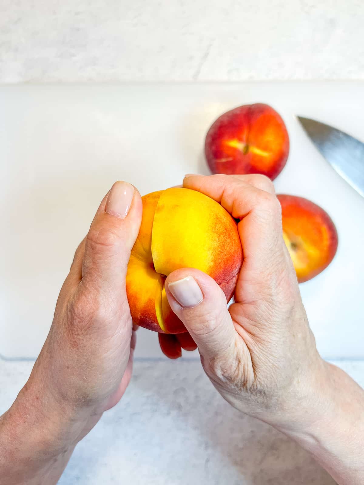 Twisting a sliced peach to remove pit.