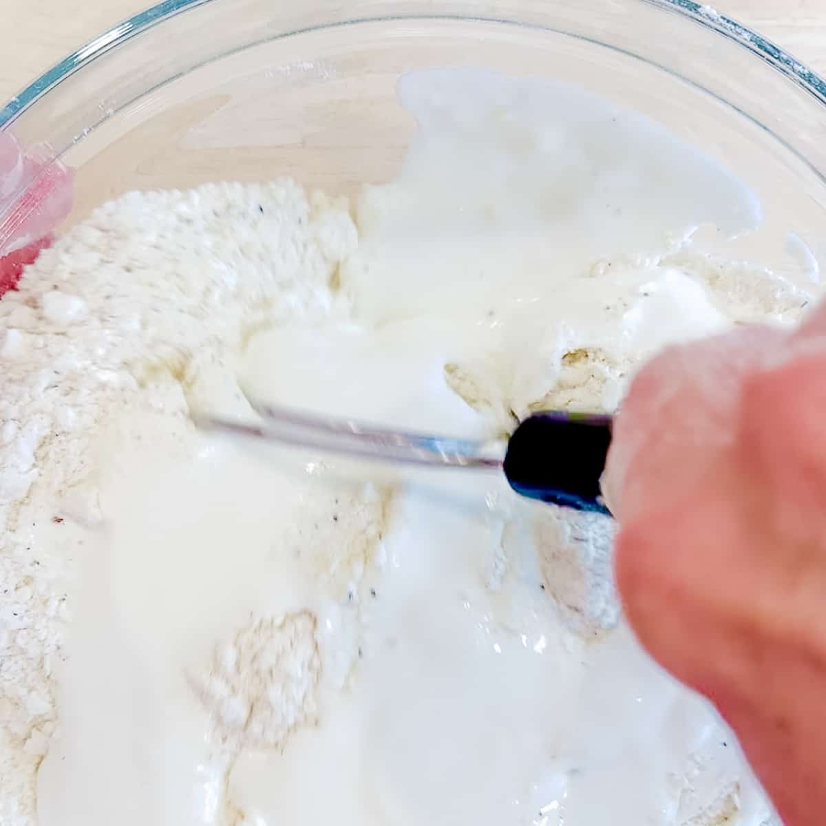 Using a dough whisk to mix biscuit dough.