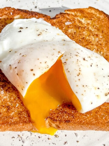 sliced open poached egg on brioche toast.