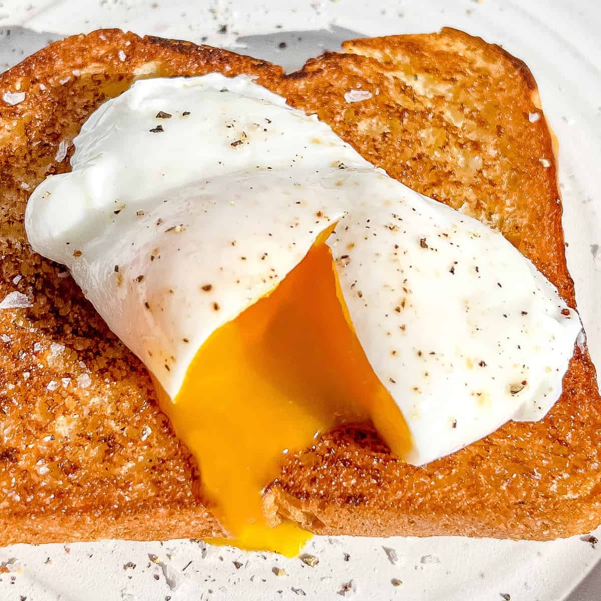 sliced open poached egg on brioche toast.