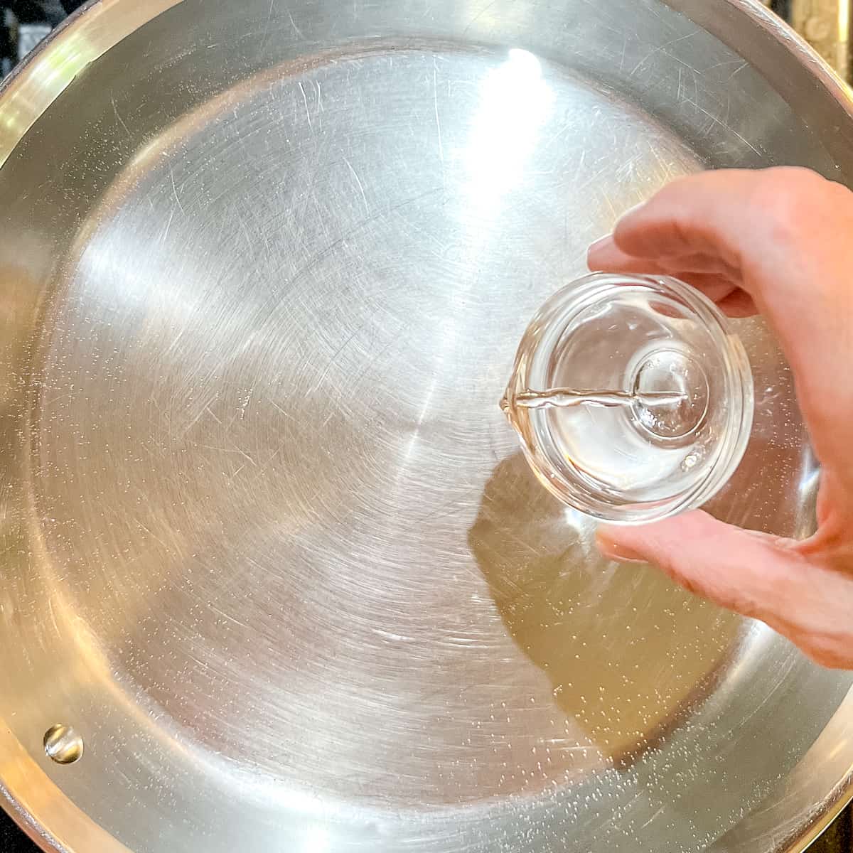 adding vinegar to water in a stainless steel skillet.