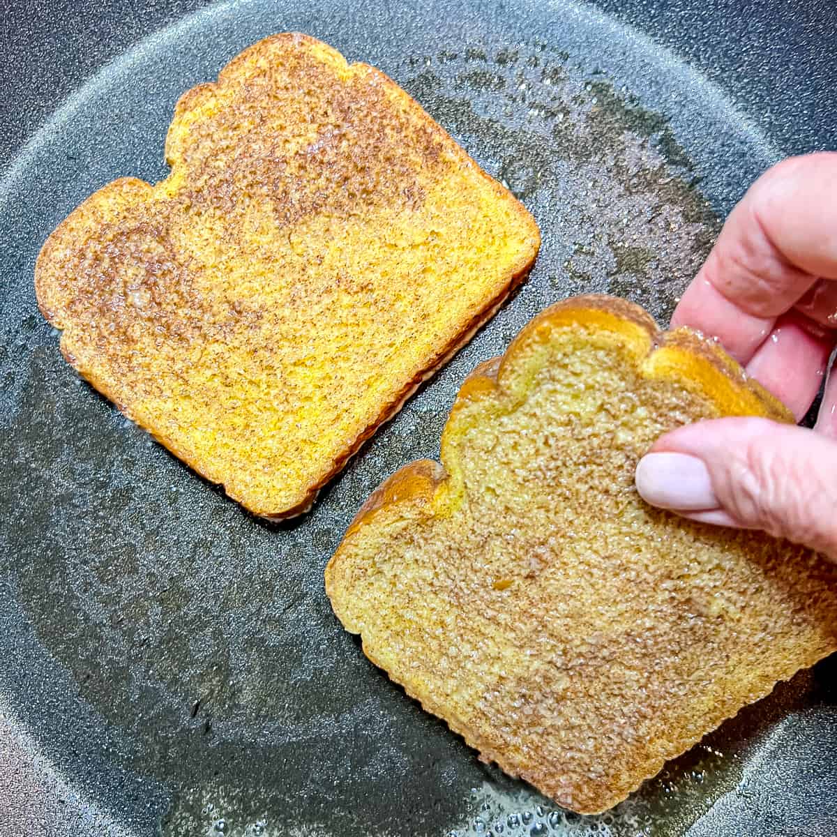 placing two pieces of french toast into a skillet.