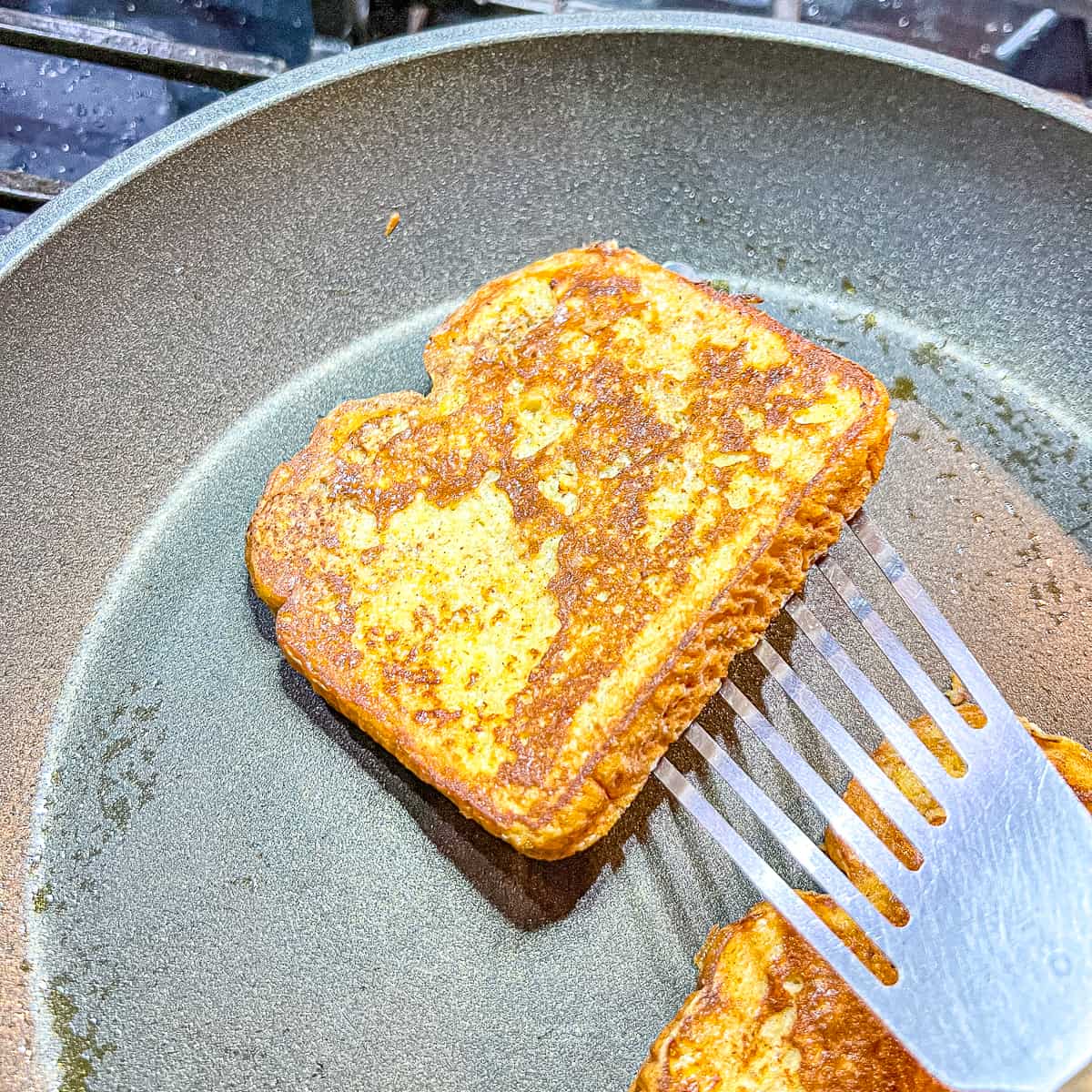 flipping over a piece of french toast in a skillet.