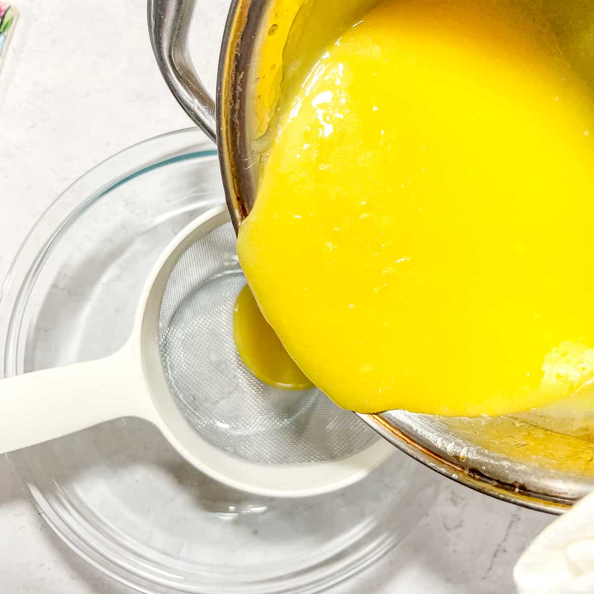 pouring lemon curd through a strainer.