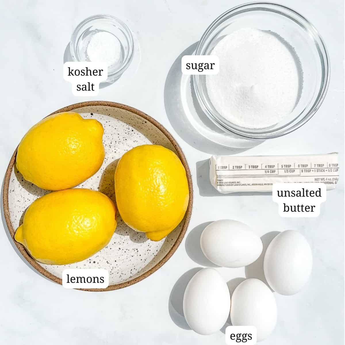 ingredients for lemon curd on a marble counter.