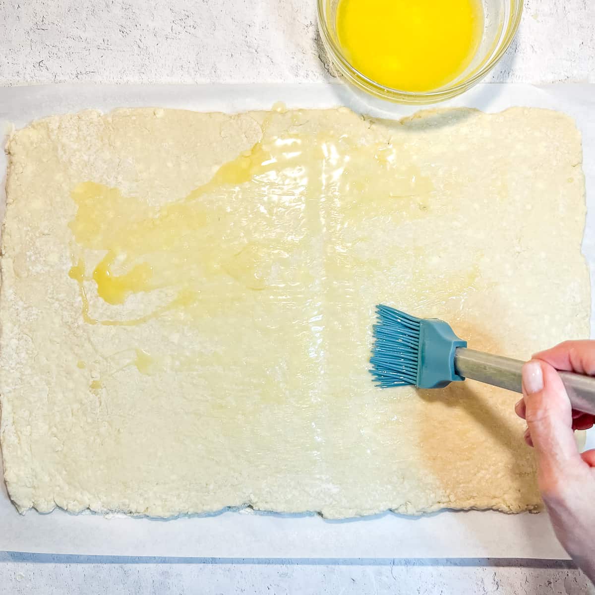 brushing butter on top of rolled dough.