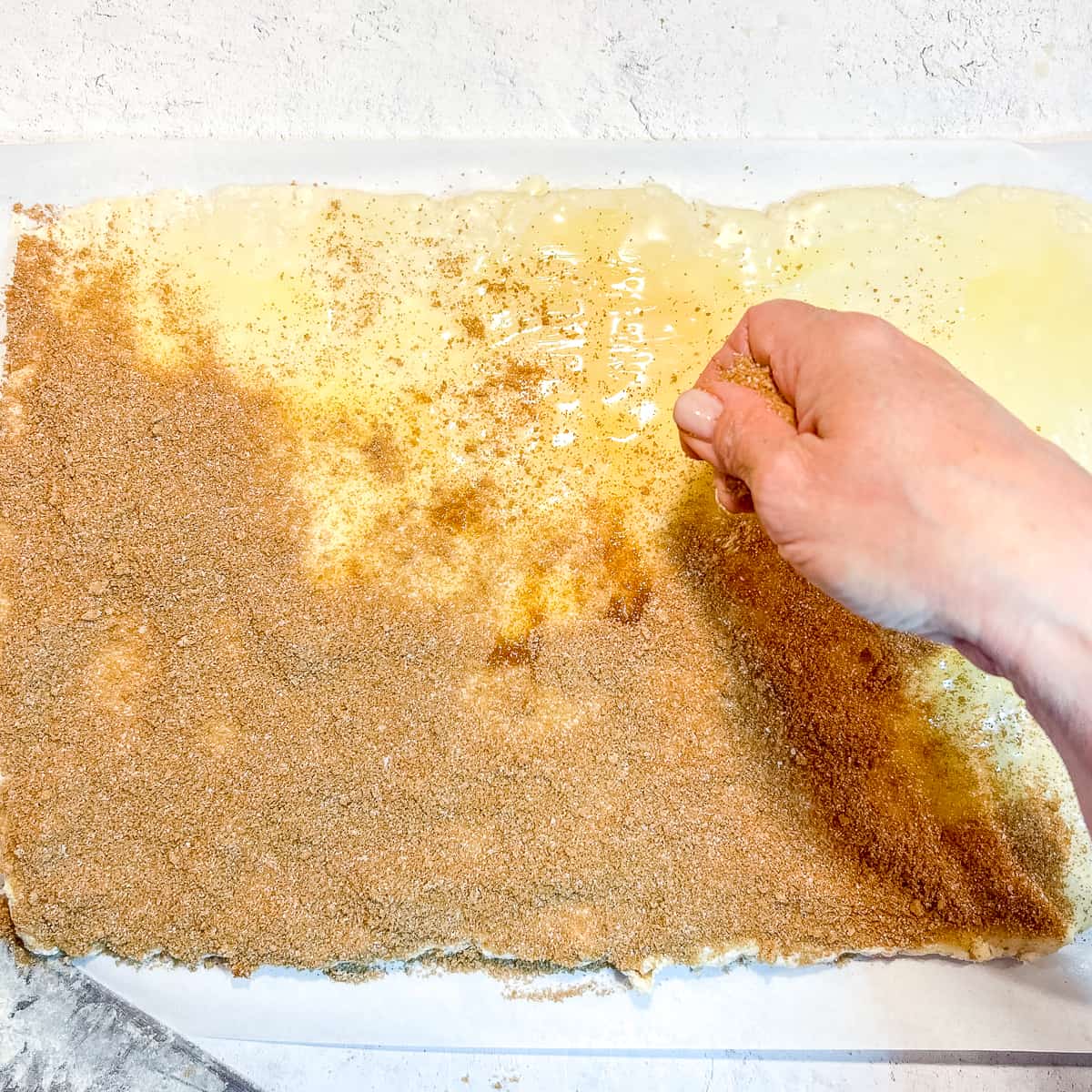 sprinkling cinnamon sugar over rolled out dough.