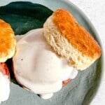 multiple biscuit eggs benedict with country gravy on a green platter.