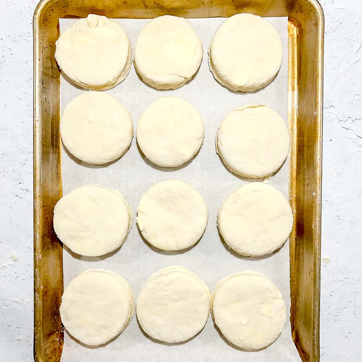 raw, cut biscuit rounds on a parchment lined baking sheet.