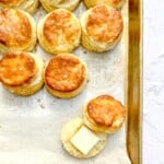 biscuits on a sheet pan, one with butter.