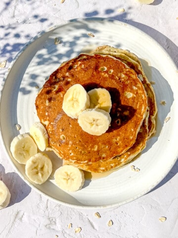 banana oat pancakes with sliced bananas on a white plate.
