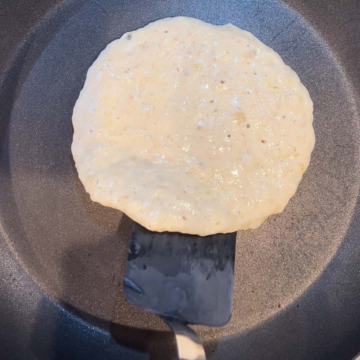 lifting the edge of a pancake with a small spatula.