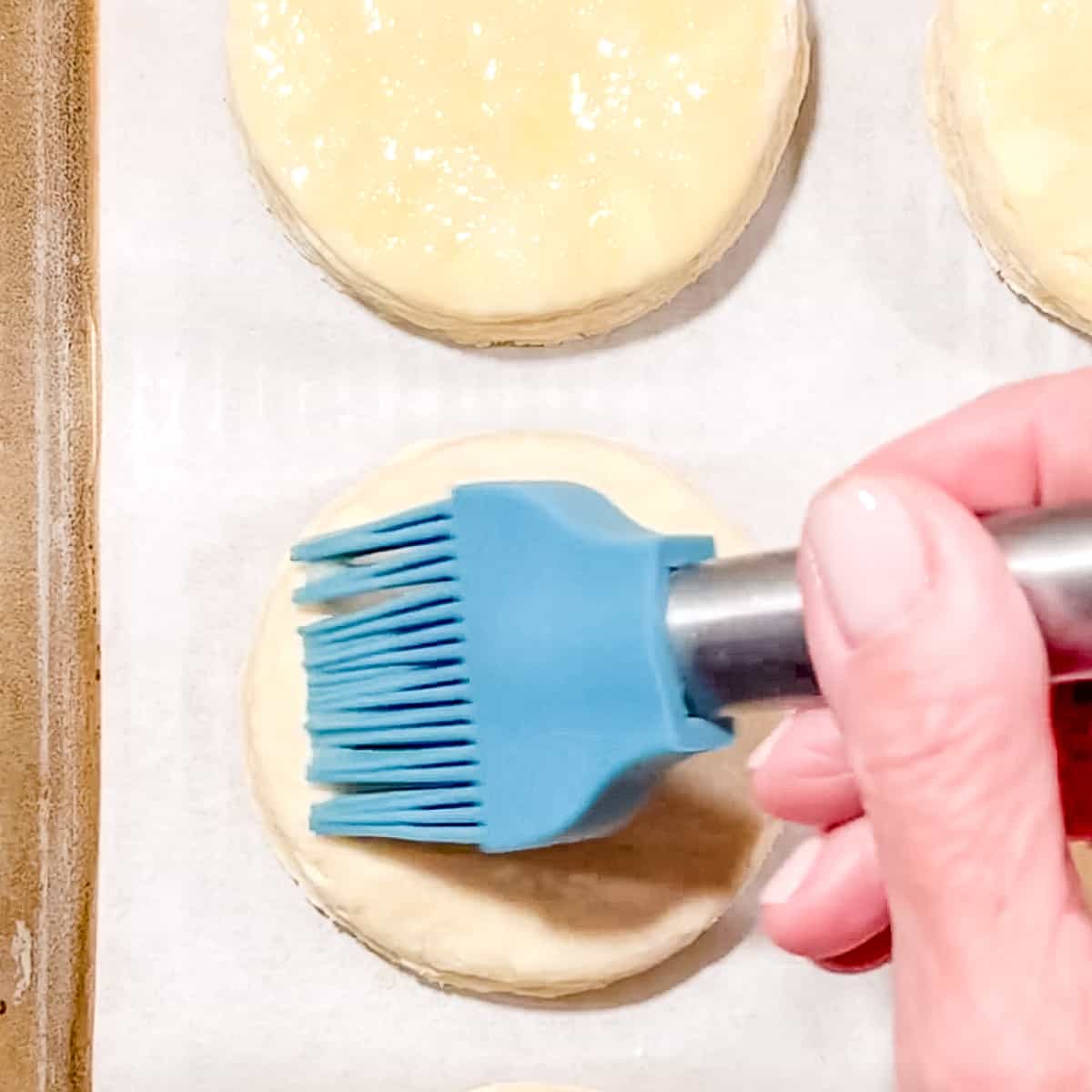 brushing egg wash on biscuits before baking.