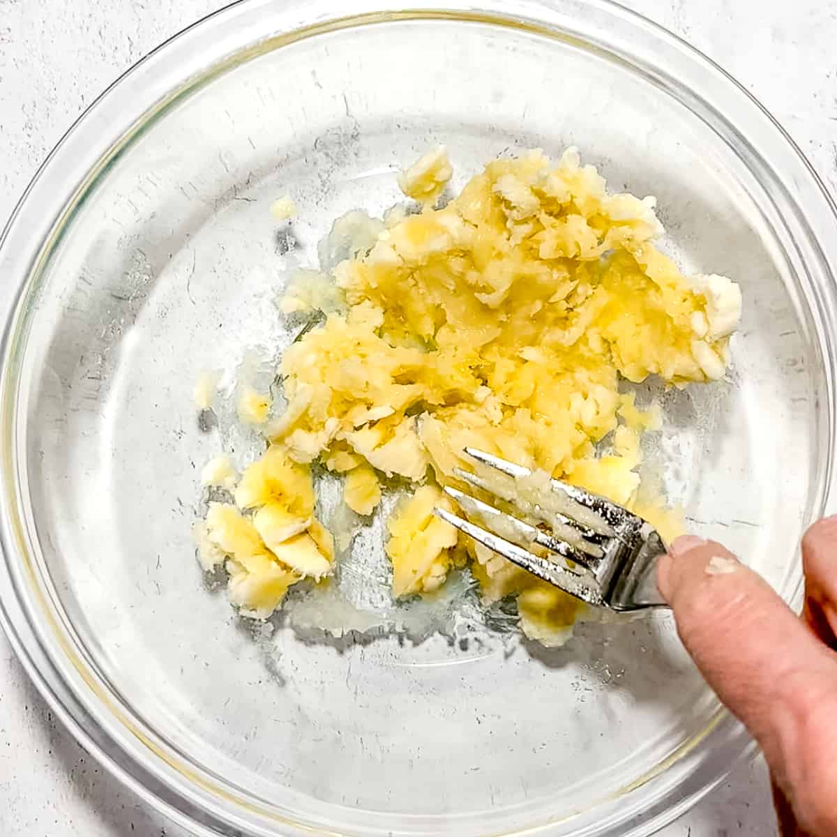 mashing banana in a bowl with fork.