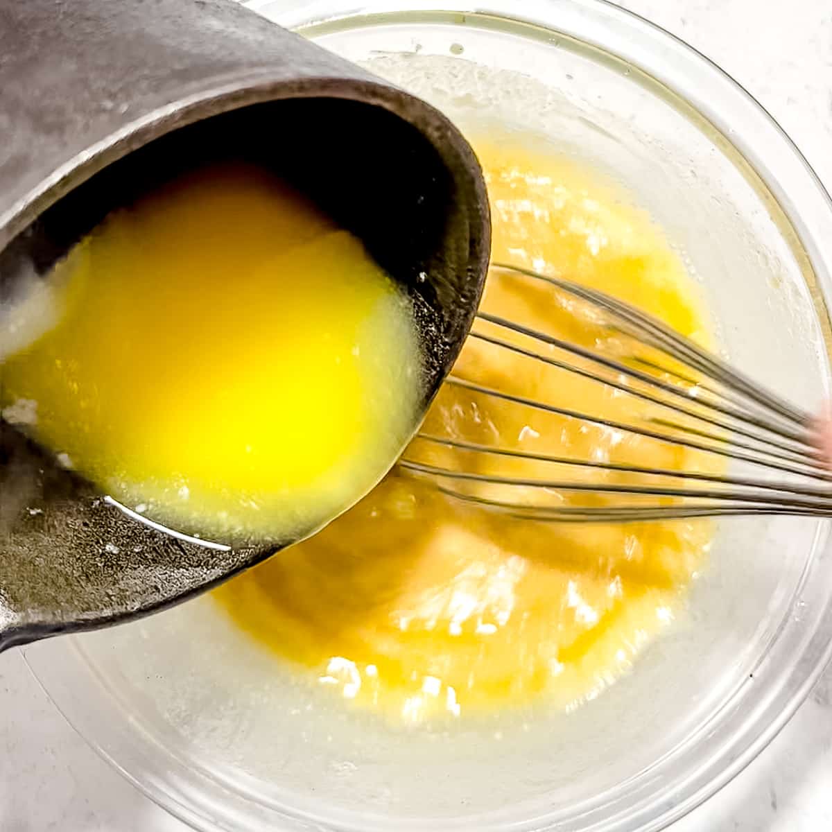 adding melted butter to wet ingredients for donuts.