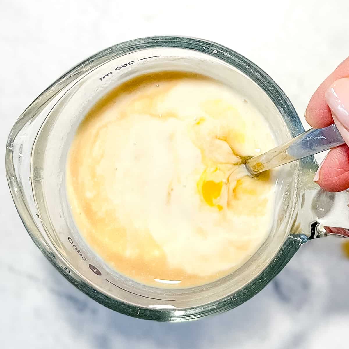 whisking wet ingredients together in a measuring cup.