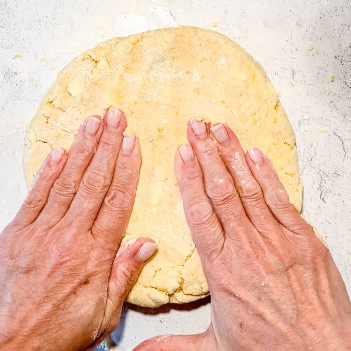 Patting scone dough into a circle with hands.