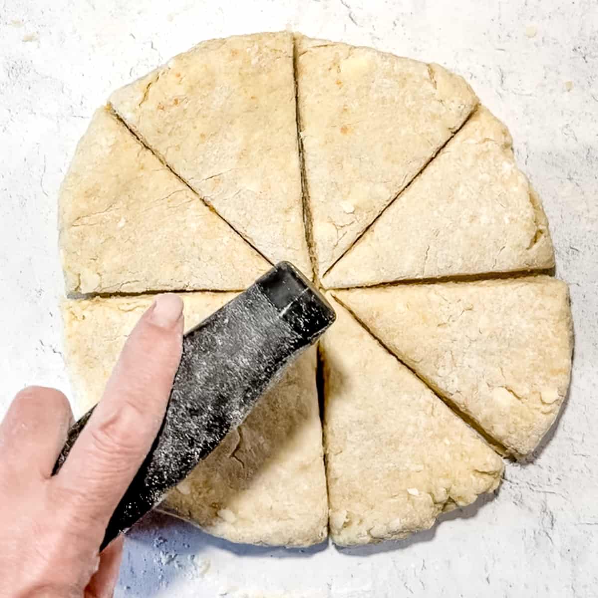 cutting scone dough into triangles with a bench scraper.