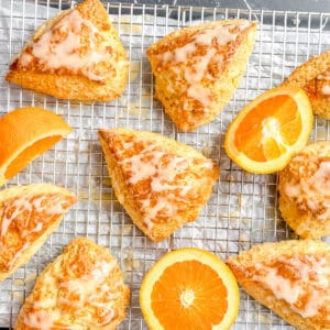 Glazed orange scones on a wire rack with orange slices