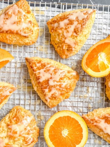 Glazed orange scones on a wire rack with orange slices