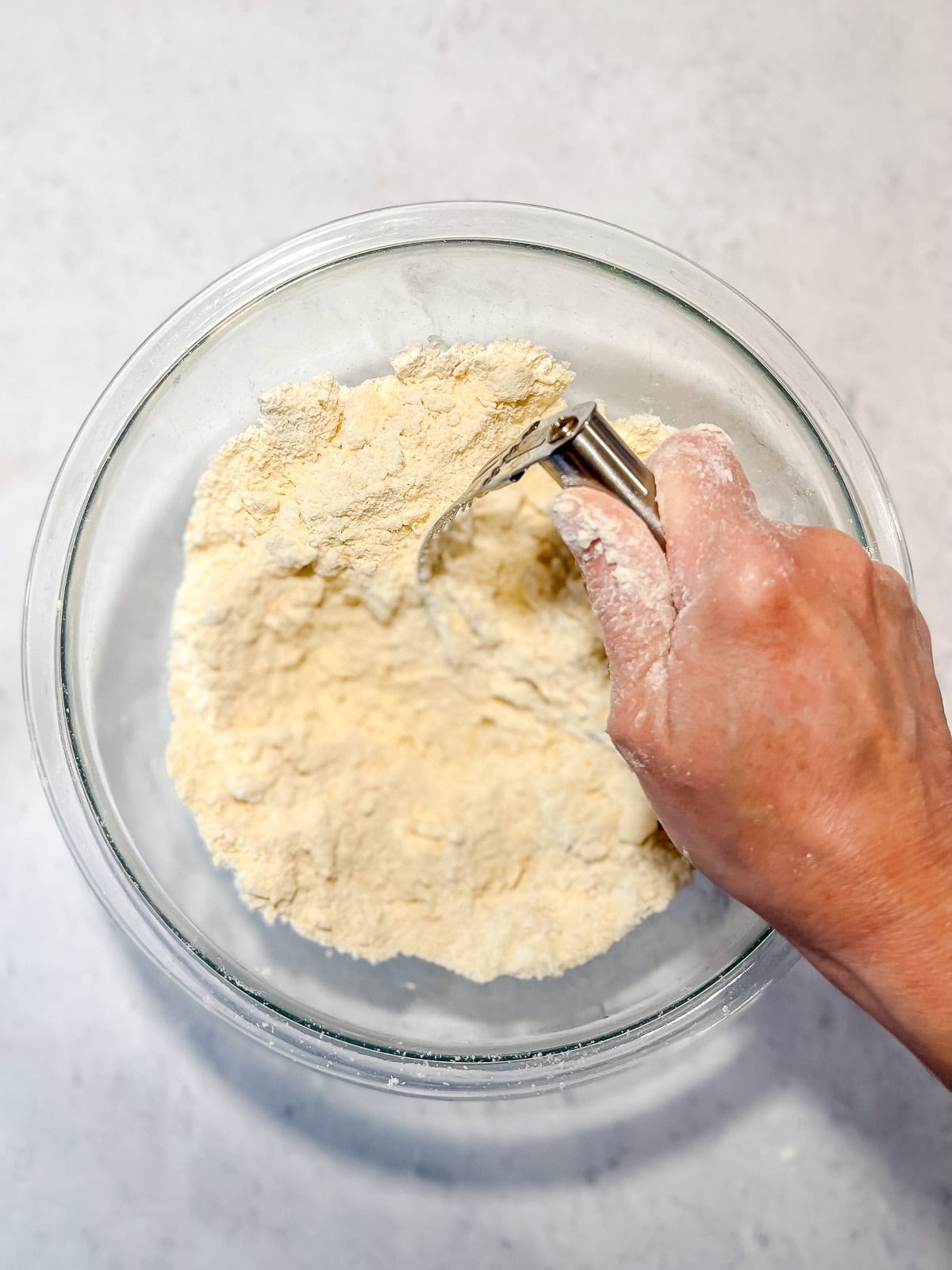 Using a pastry cutter to cut butter into dry ingredients.