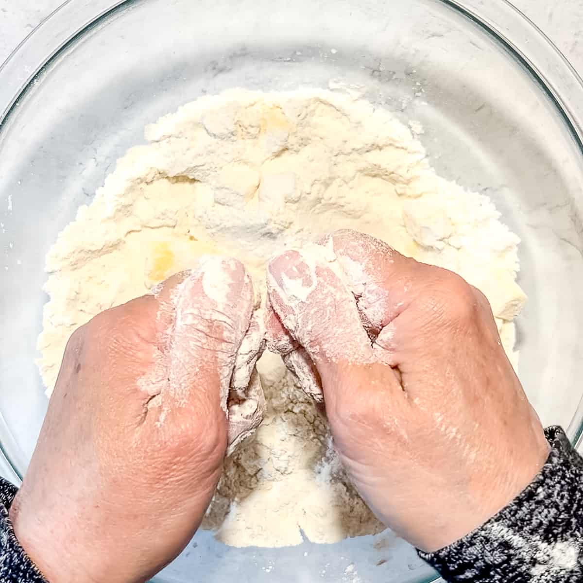 using fingers to combine butter cubes with biscuit dry ingredients.