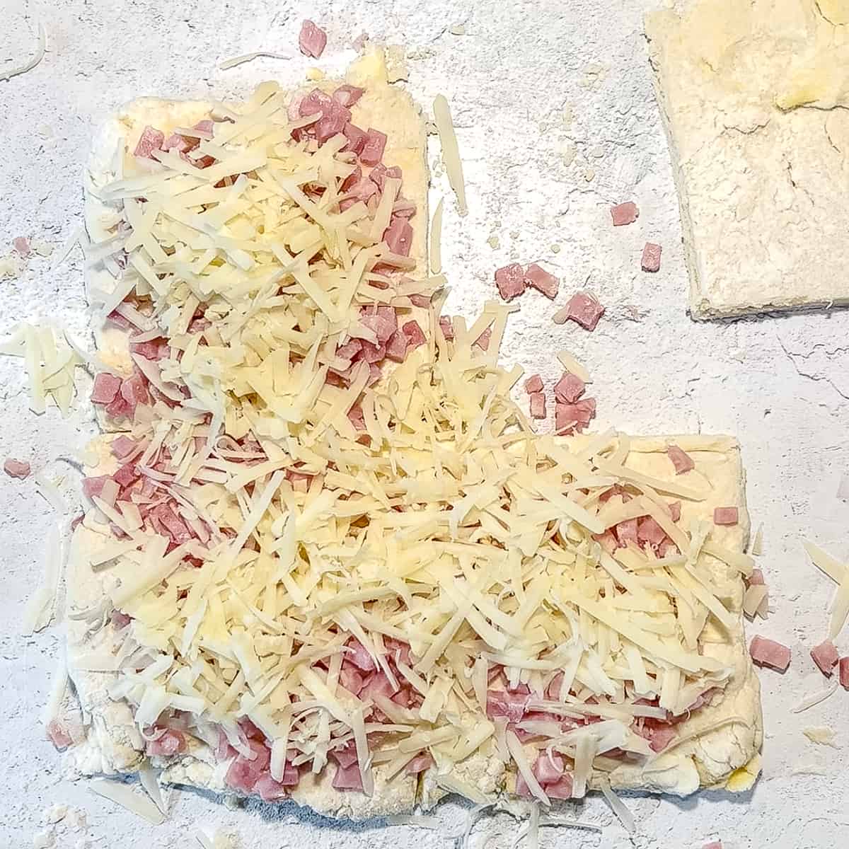 sprinkling ham and swiss over 3 of the 4 squares of biscuit dough.
