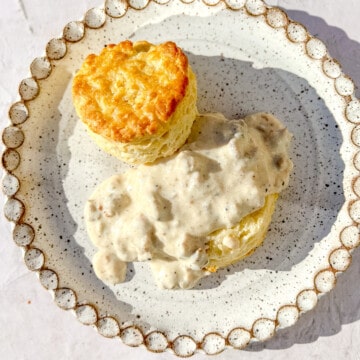 biscuits and gravy on a white speckled plate.