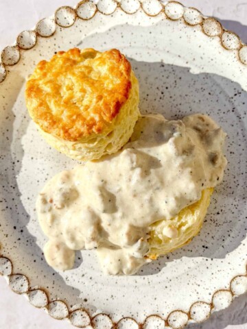 biscuits and gravy on a white speckled plate.