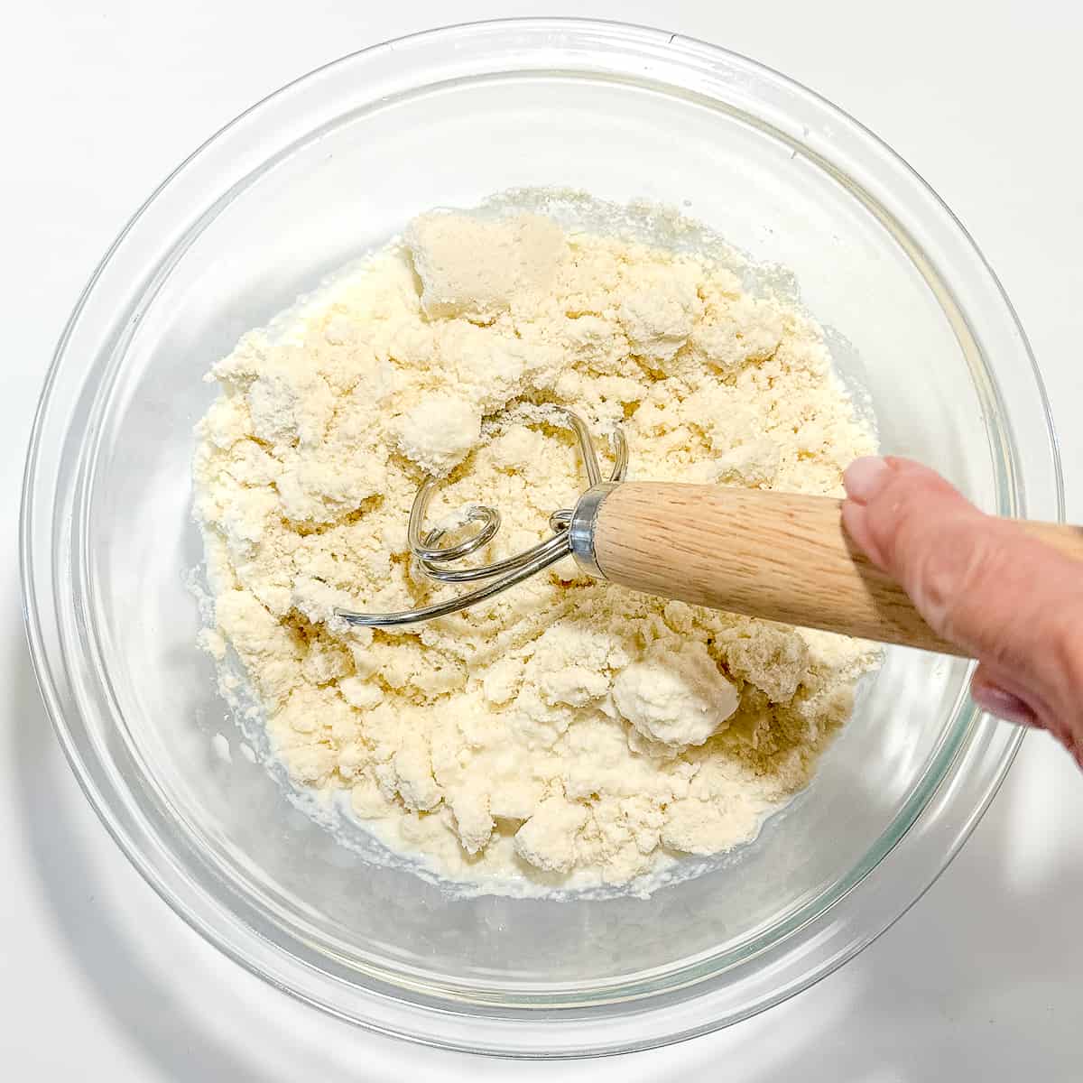 using a dough whisk to mix milk into buttermilk biscuit mix.