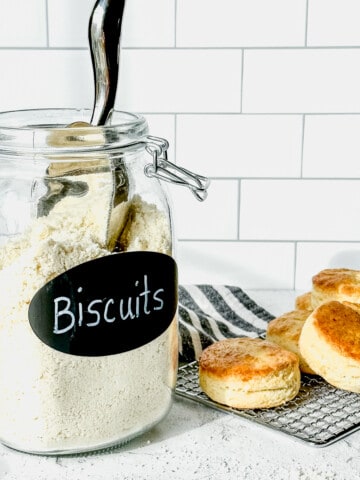 a container of buttermilk biscuit mix next to a tray of baked biscuits.