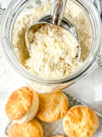 top view of a container of buttermilk biscuit mix next to a tray of baked biscuits.