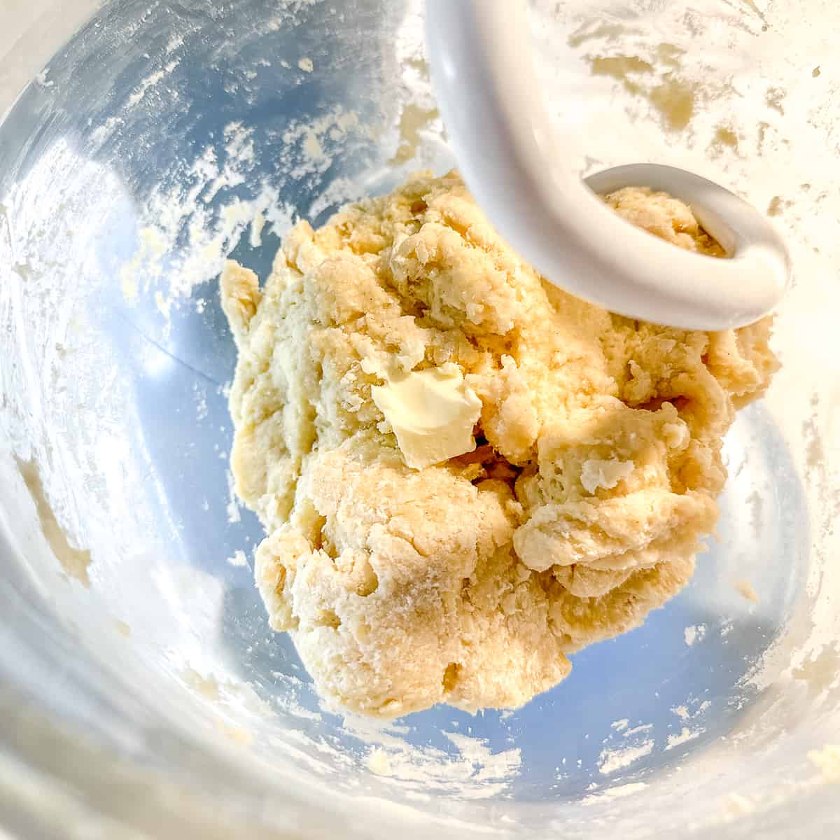 adding butter to brioche dough in mixer.