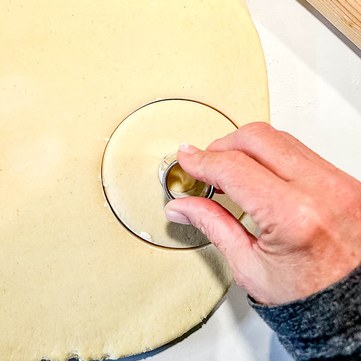 using a small round cutter to cut a hole in a donut.