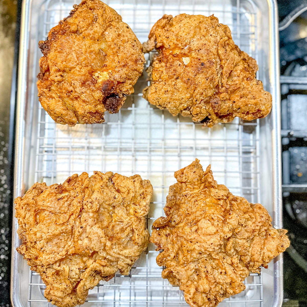 korean fried chicken on a wire rack in a sheet pan.