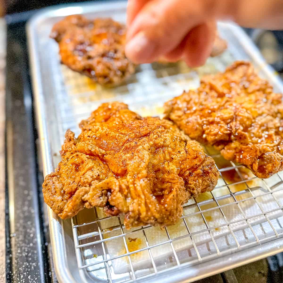 sprinkling korean spice mix on a piece of fried chicken.