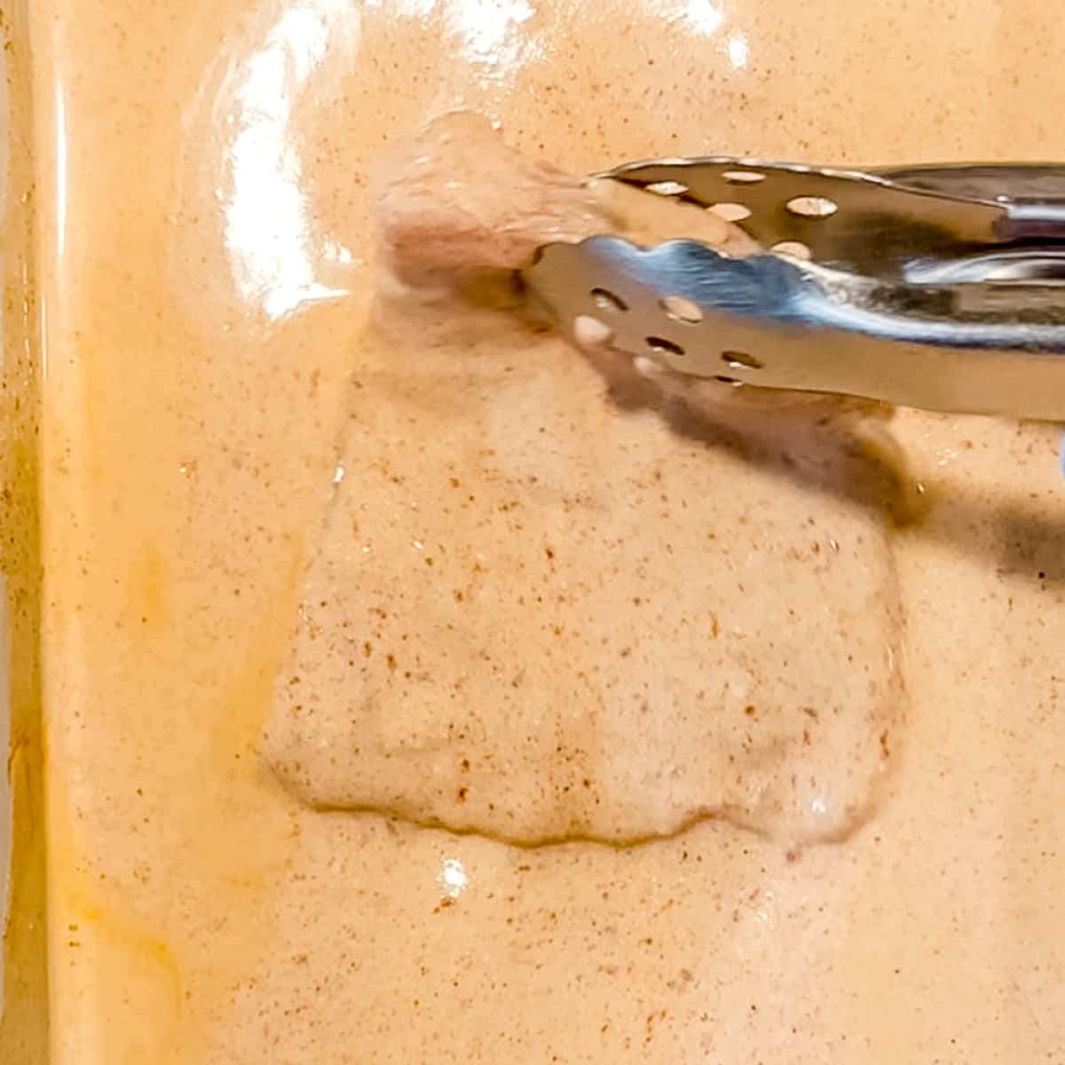 placing chicken pieces in buttermilk brine for korean fried chicken.