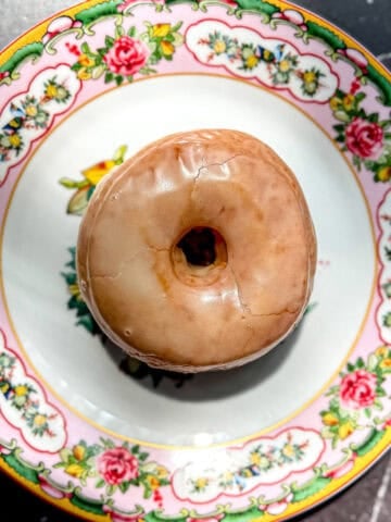 Glazed donut on a floral plate.