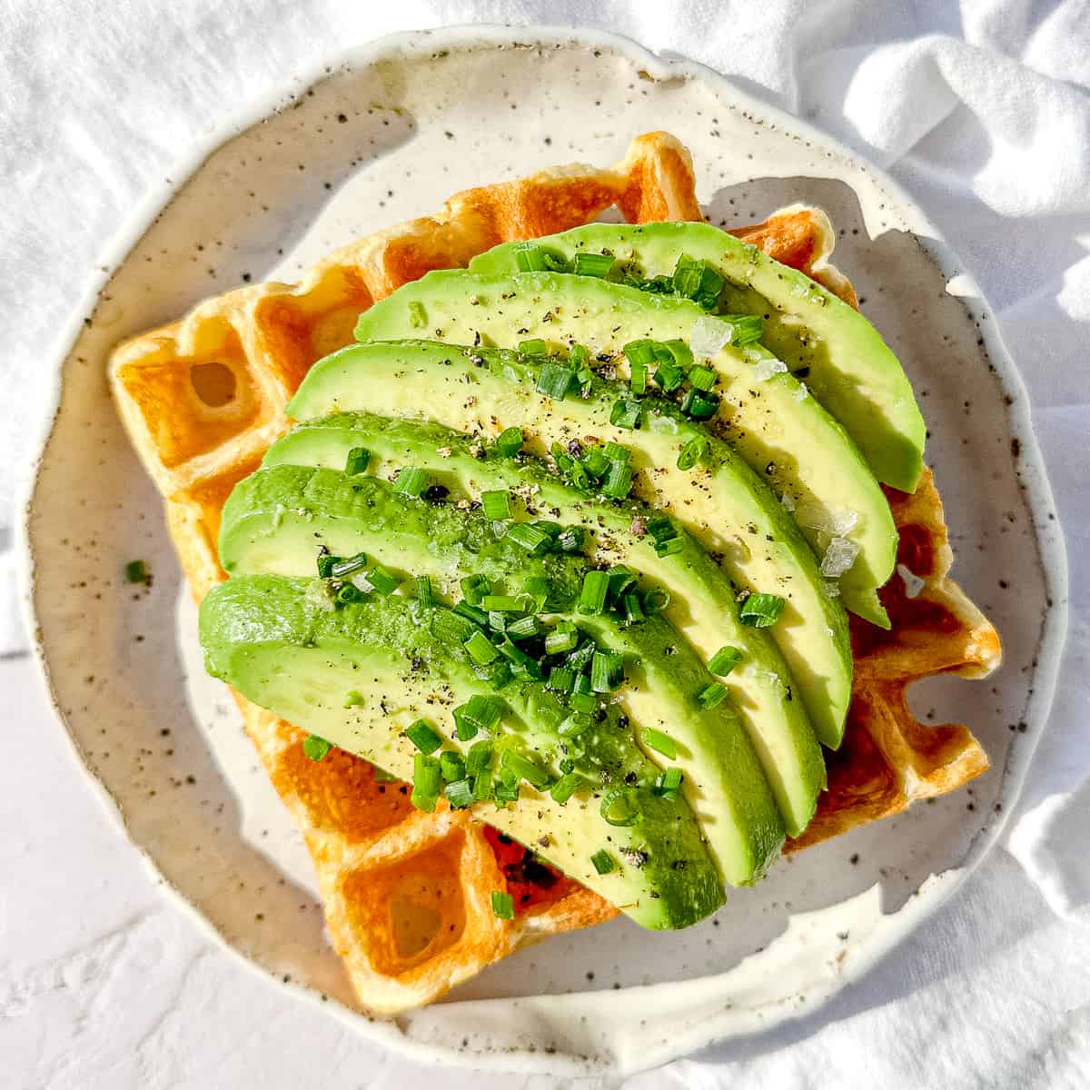 waffle with avocado slices and chives.