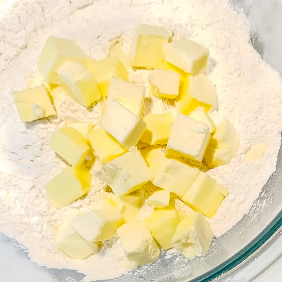 adding cold cubed butter to biscuit dry ingredients.