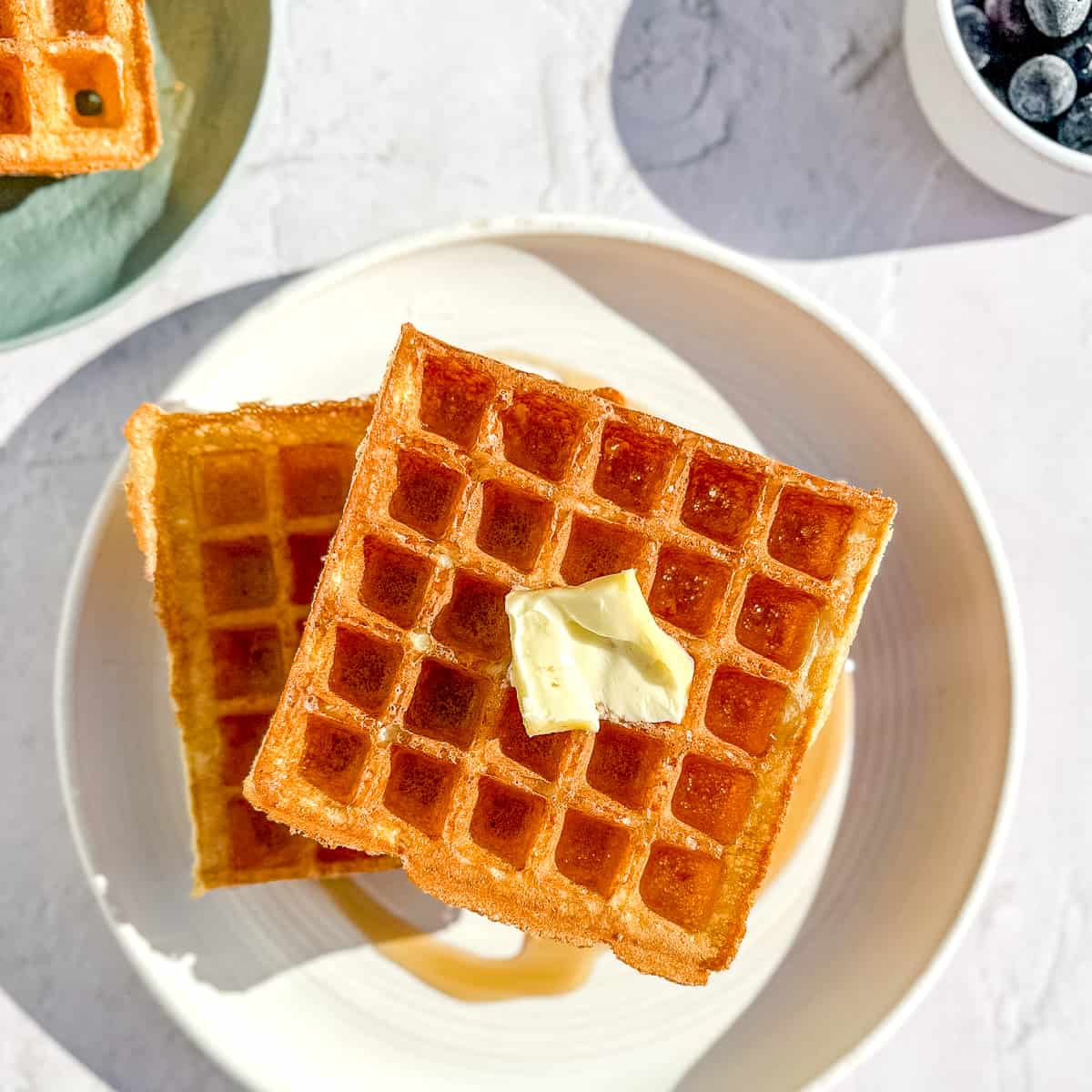 yeast waffles with a bowl of blueberries.