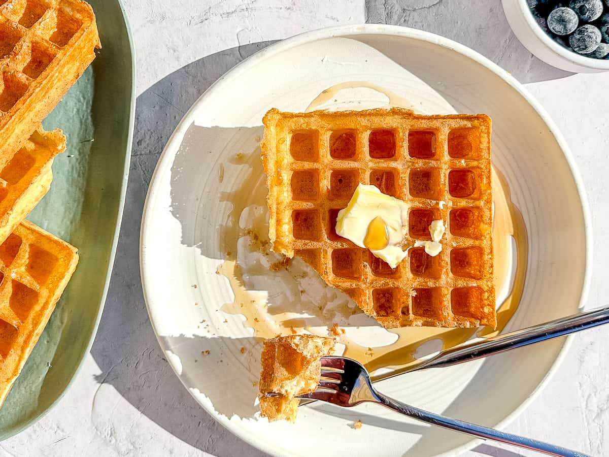 horizontal view of yeast waffles with butter and syrup.