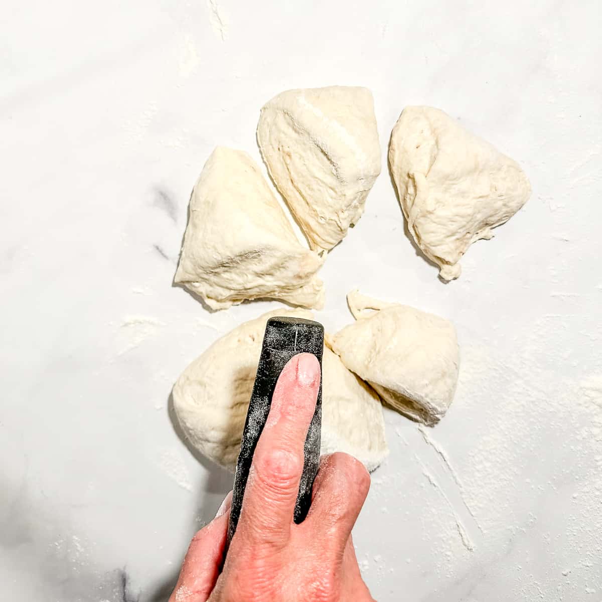 using a bench scraper to cut dough into six pieces.