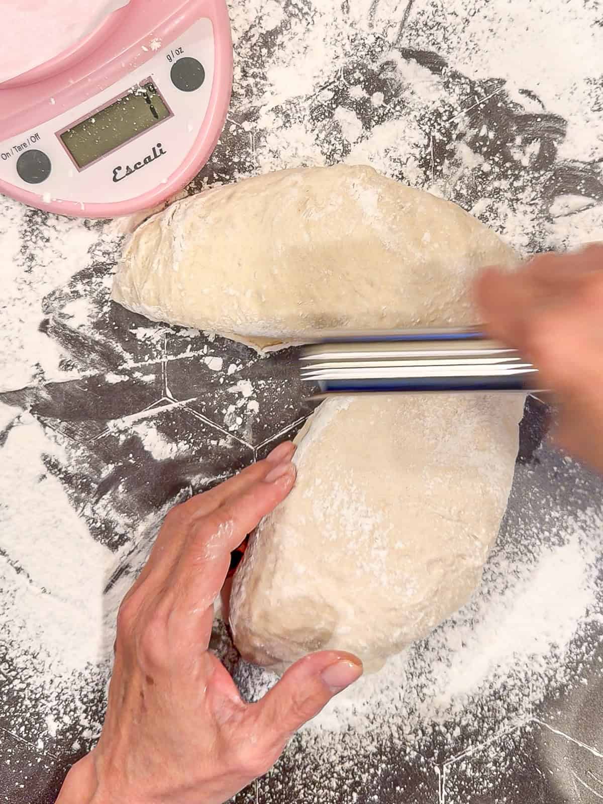 Using a bench scraper to divide bread dough.