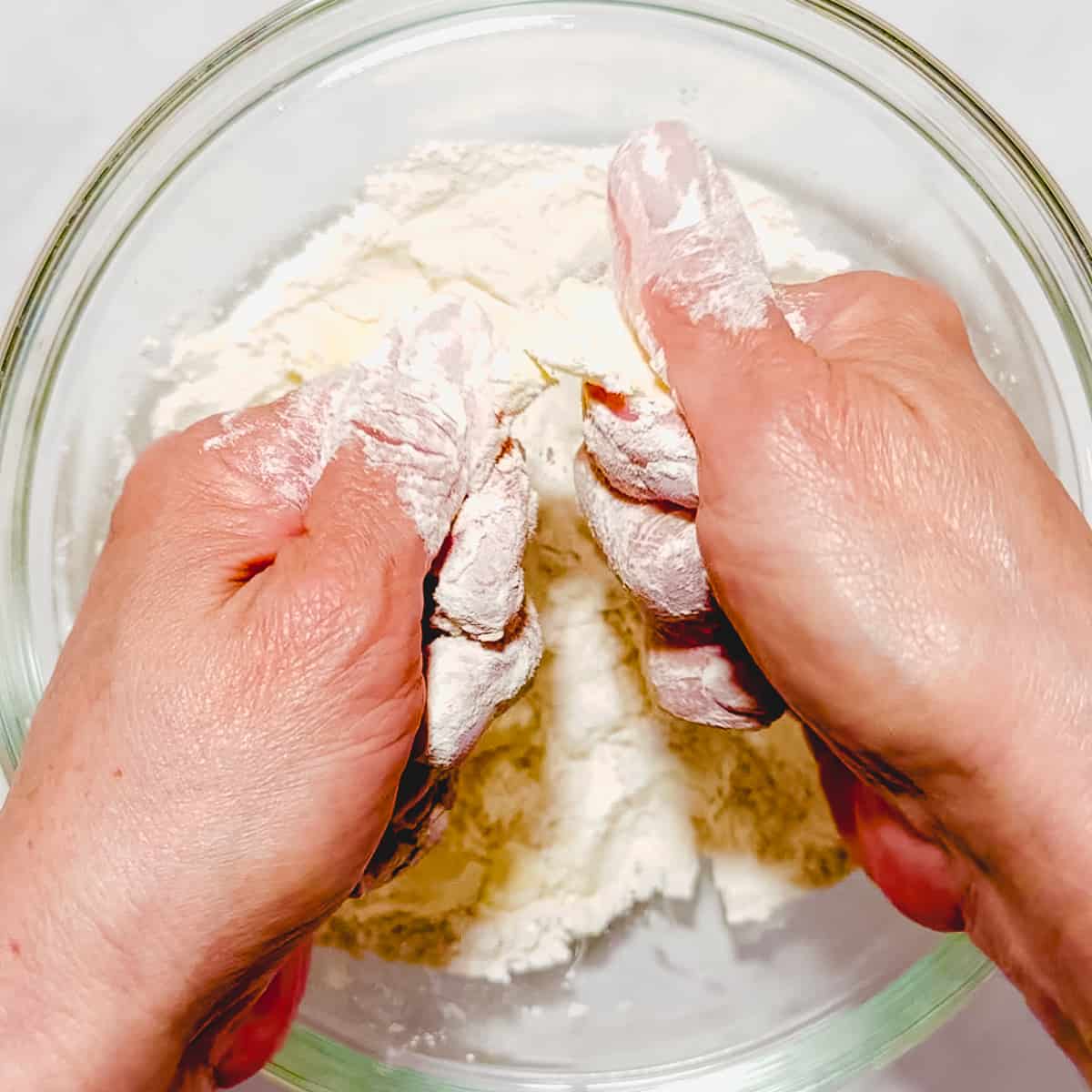 using fingers to combine butter with dry ingredients for biscuits.